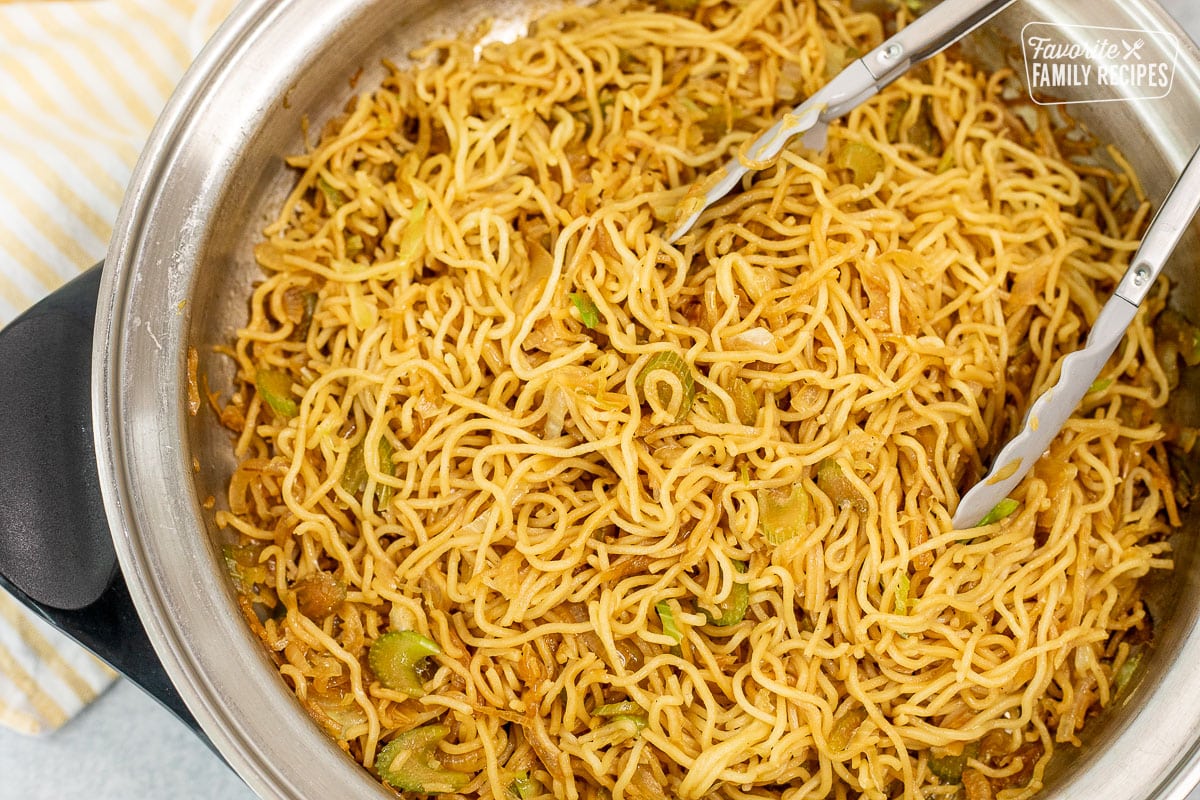 Cooked Chow Mein Noodles with tongs in a large skillet.