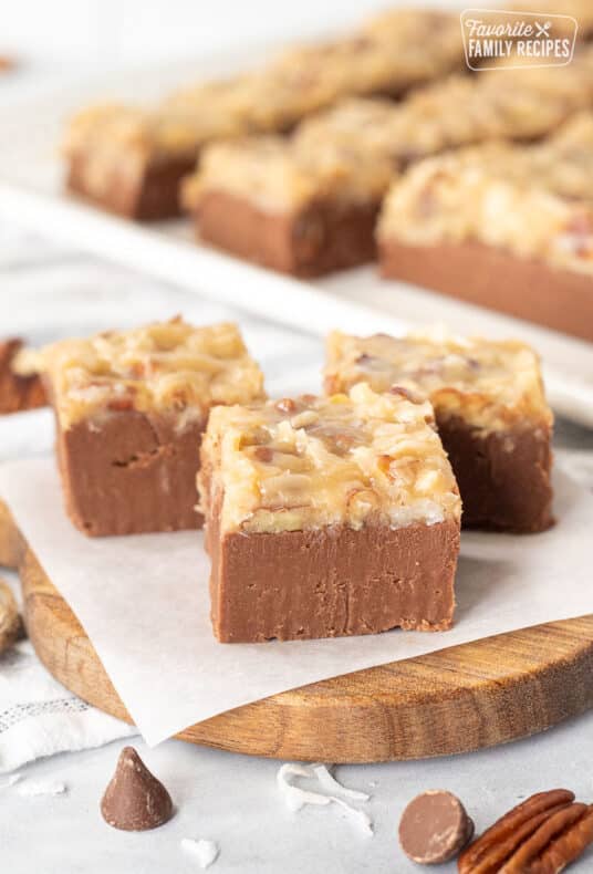 Three pieces of German Chocolate Fudge on a cutting board lined with parchment paper.