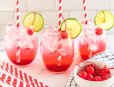 three shirley temples garnished with cherries and lime