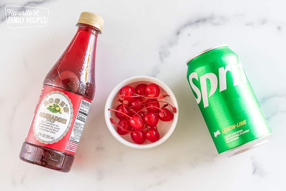 A can of sprite, a bowl of maraschino cherries, and a bottle of grenadine