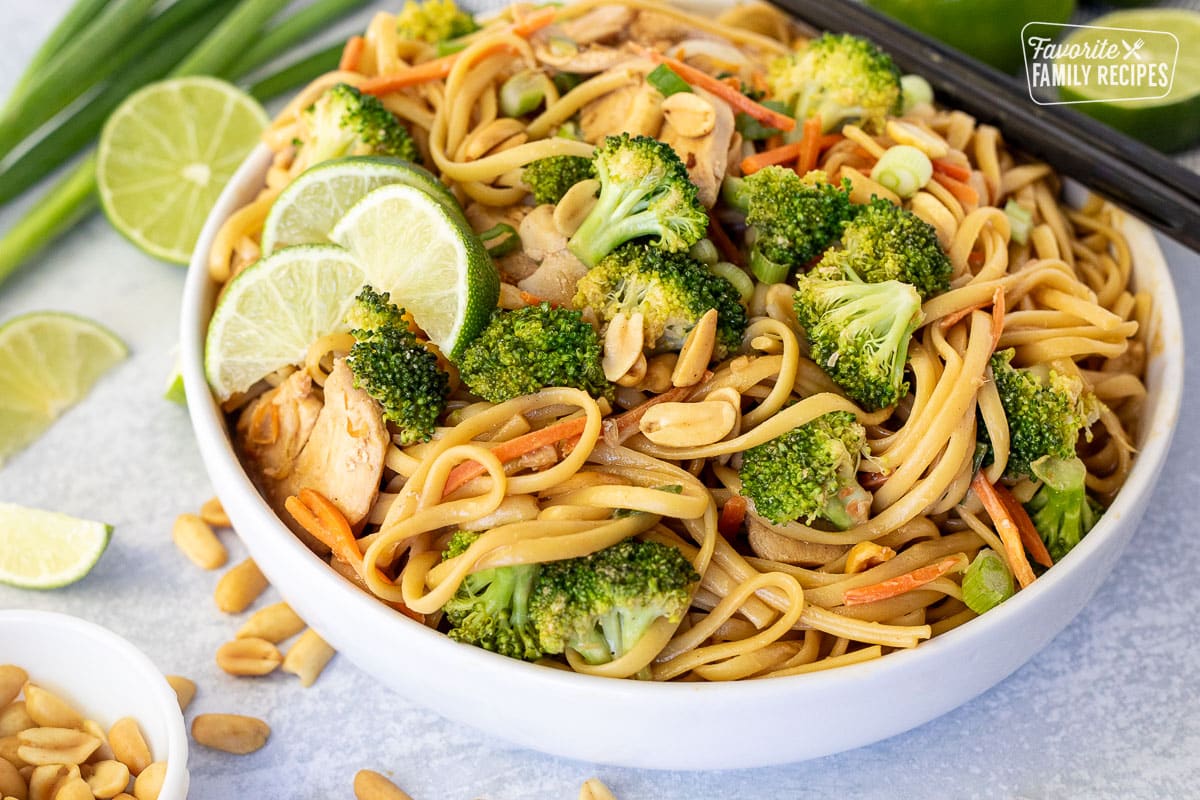 Bol of Peanut Noodles with broccoli, carrots and limes.