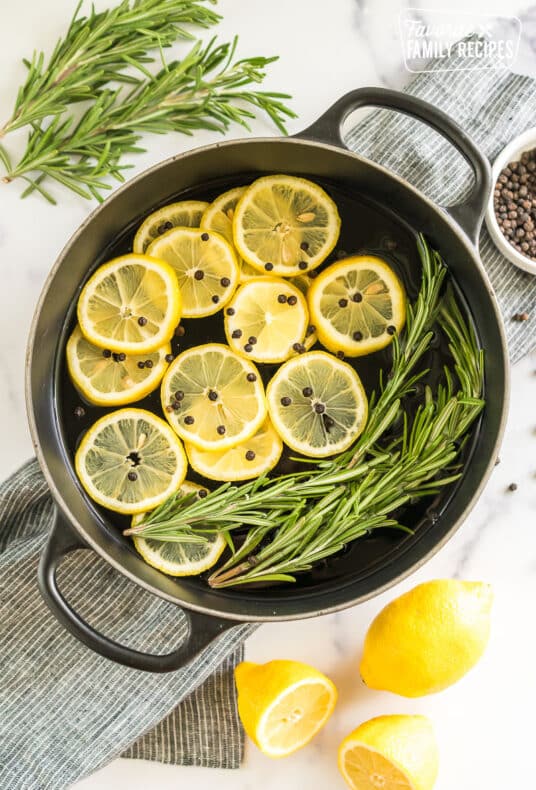 A simmer pot filled with water, lemon slices, peppercorns, rosemary sprigs, and vanilla extract