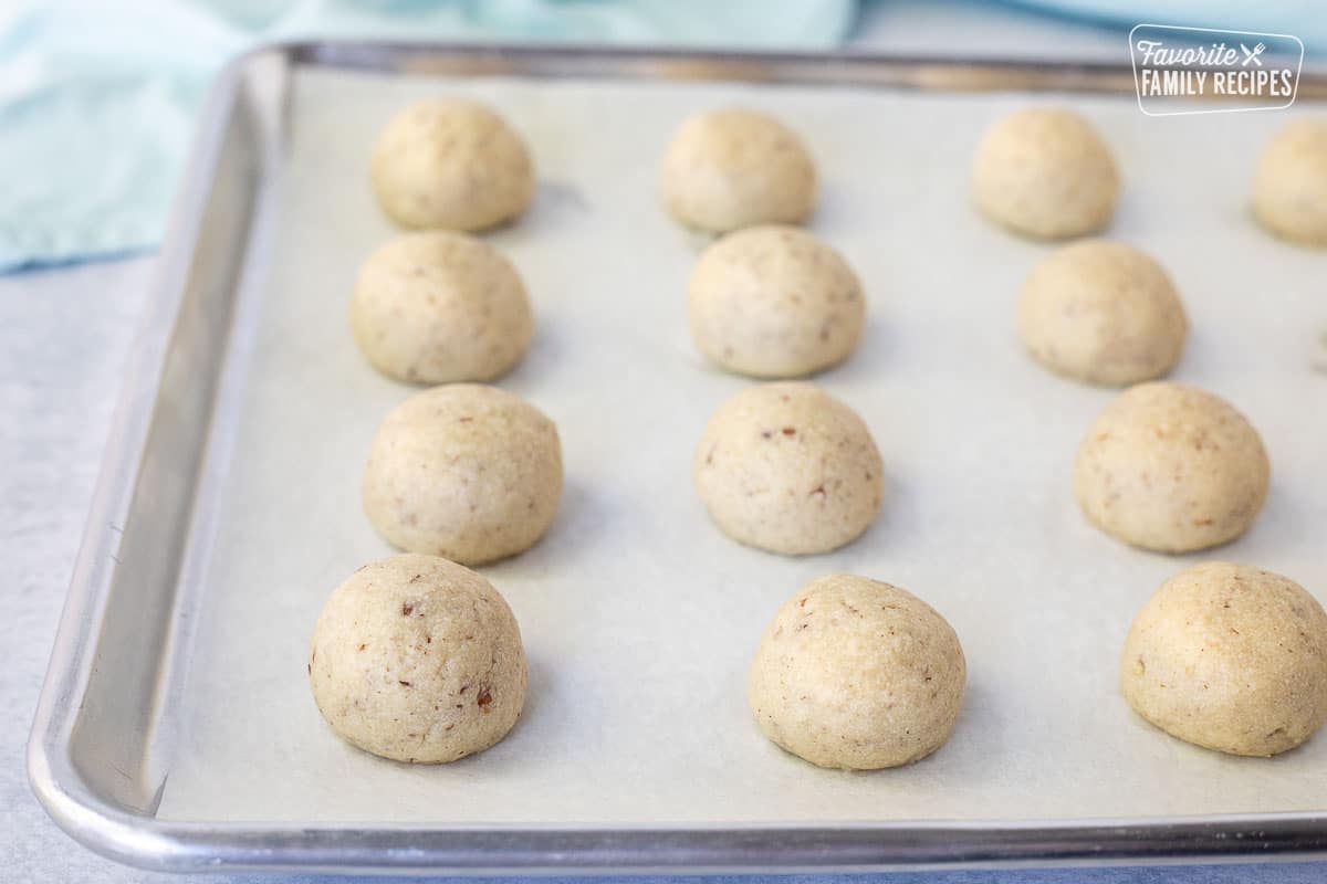 Baked Snowball Cookies on a cookie sheet with parchment paper.