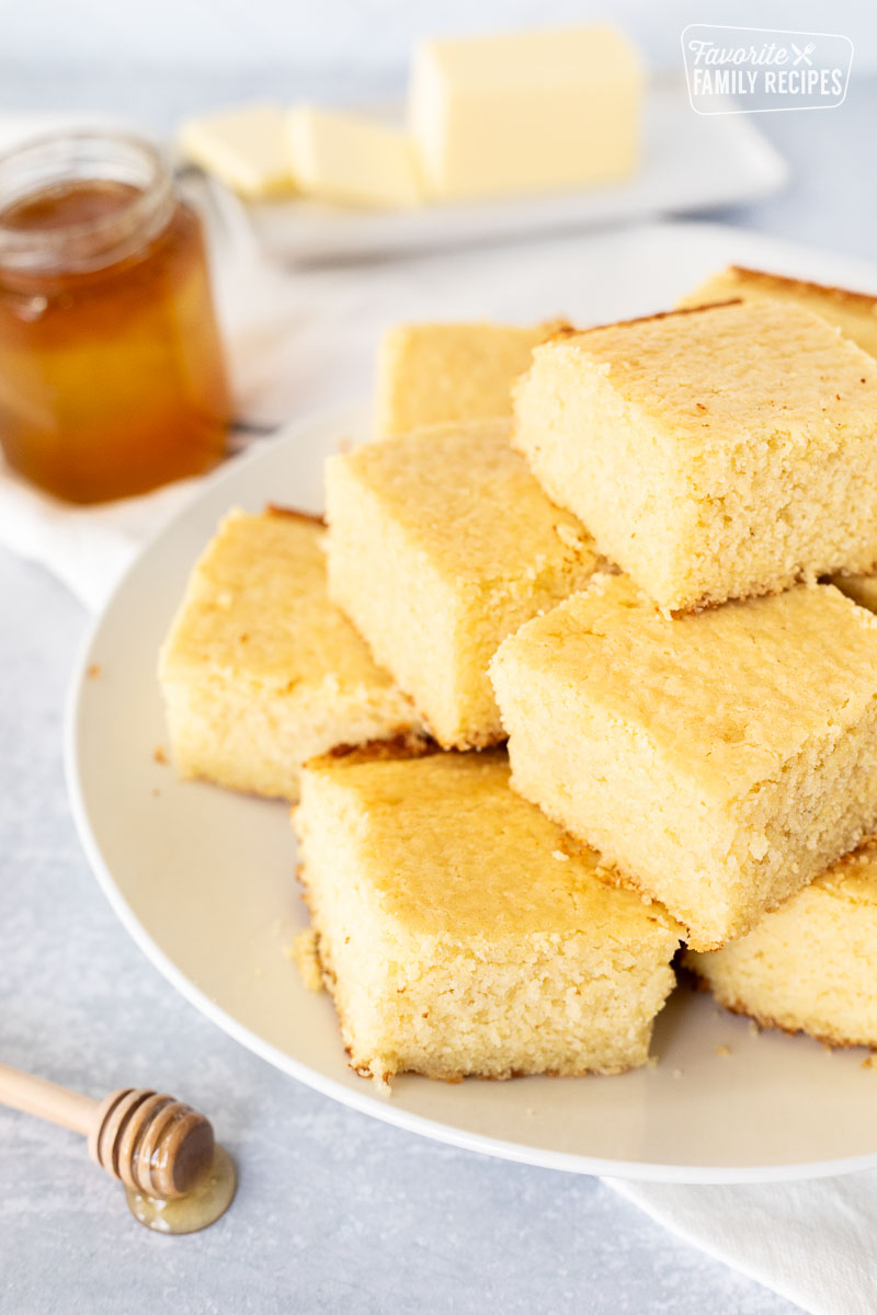 Plate of sliced cornbread. Honey and butter on the side.