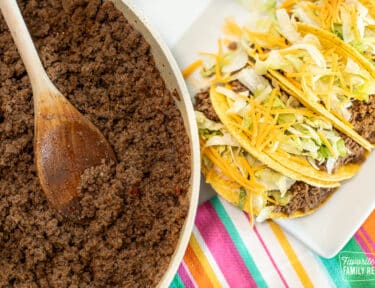 A skillet with Taco Bell meat next to a plate of homemade Taco Bell tacos