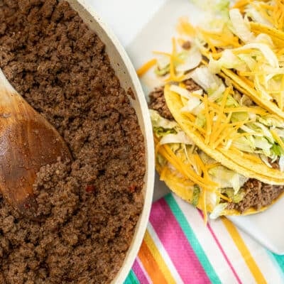 A skillet with Taco Bell meat next to a plate of homemade Taco Bell tacos