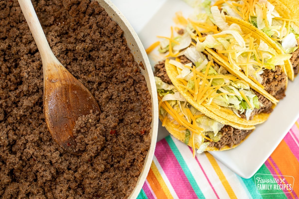 A skillet with Taco Bell meat next to a plate of homemade Taco Bell tacos