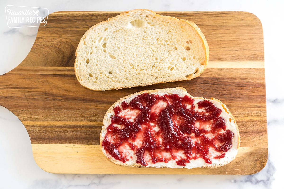 two slices of bread; one spread with cream cheese and cranberry sauce
