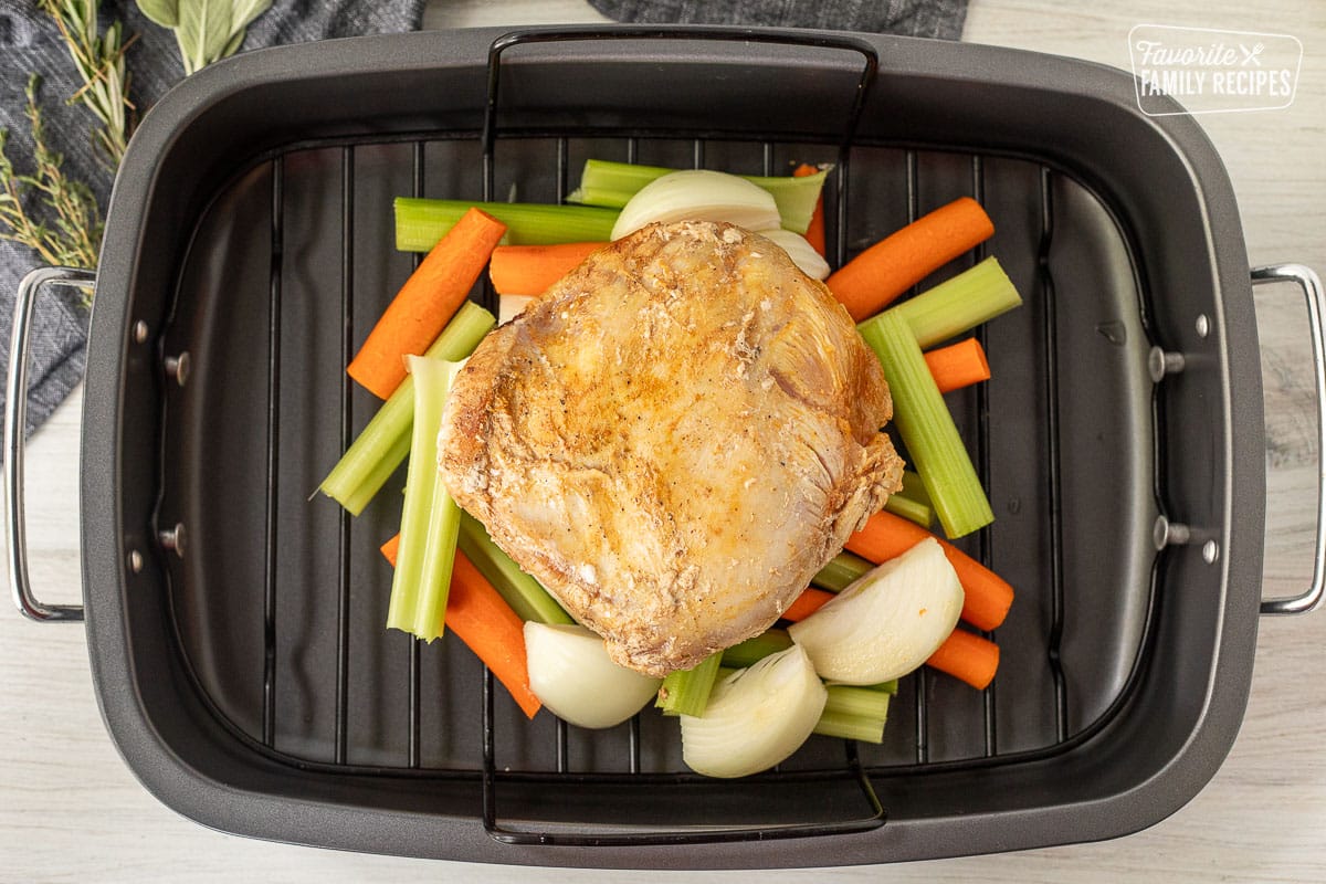 Roasting pan with seared turkey breast, cut carrots, celery and onions.