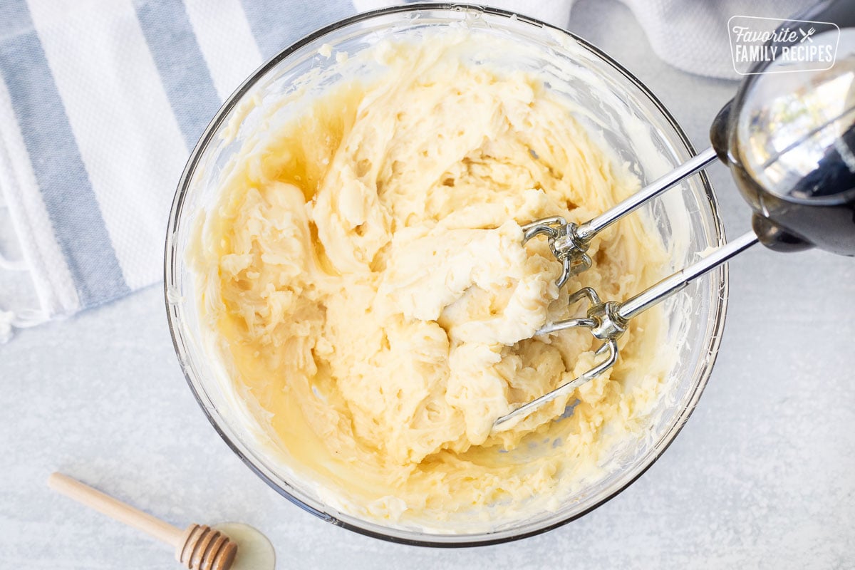 Mixing bowl of butter and honey with beaters.