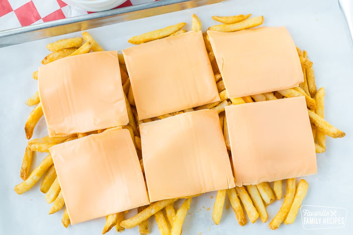 American cheese layered over French fries on a baking sheet