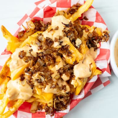 A top view of animal style fries in a basket lined with checkered paper
