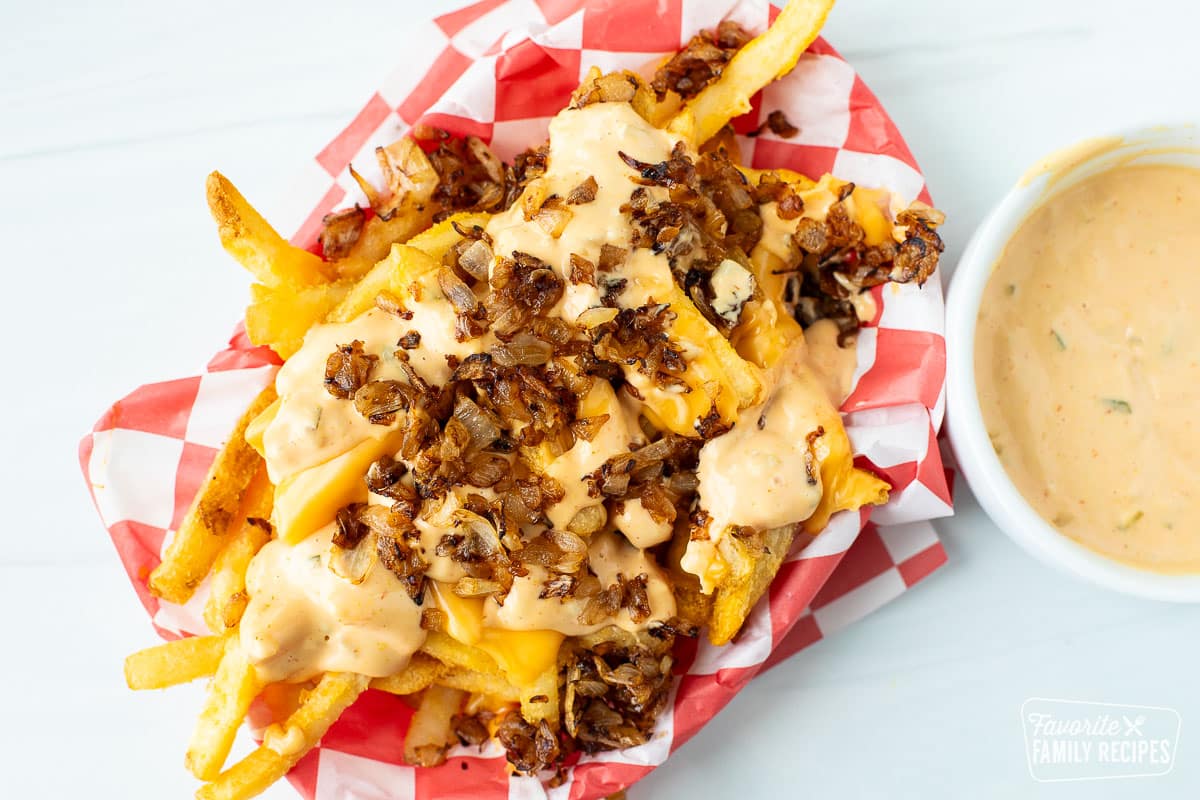 A top view of animal style fries in a basket lined with checkered paper