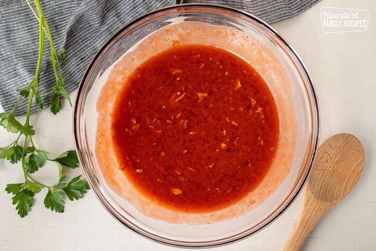 Mixing bowl with marinade mixture for Apricot Chicken. Wooden spoon on the side.