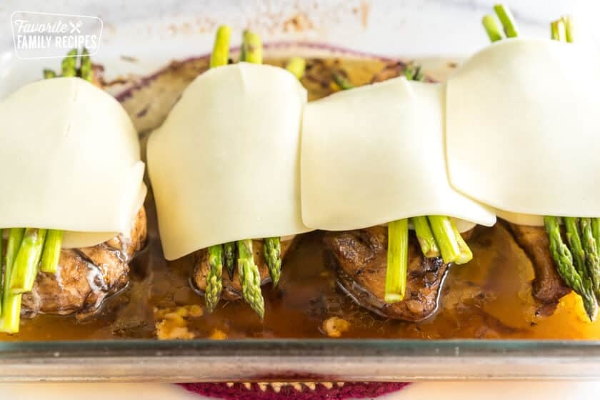 Chicken breasts in a pan with asparagus and cheese slices