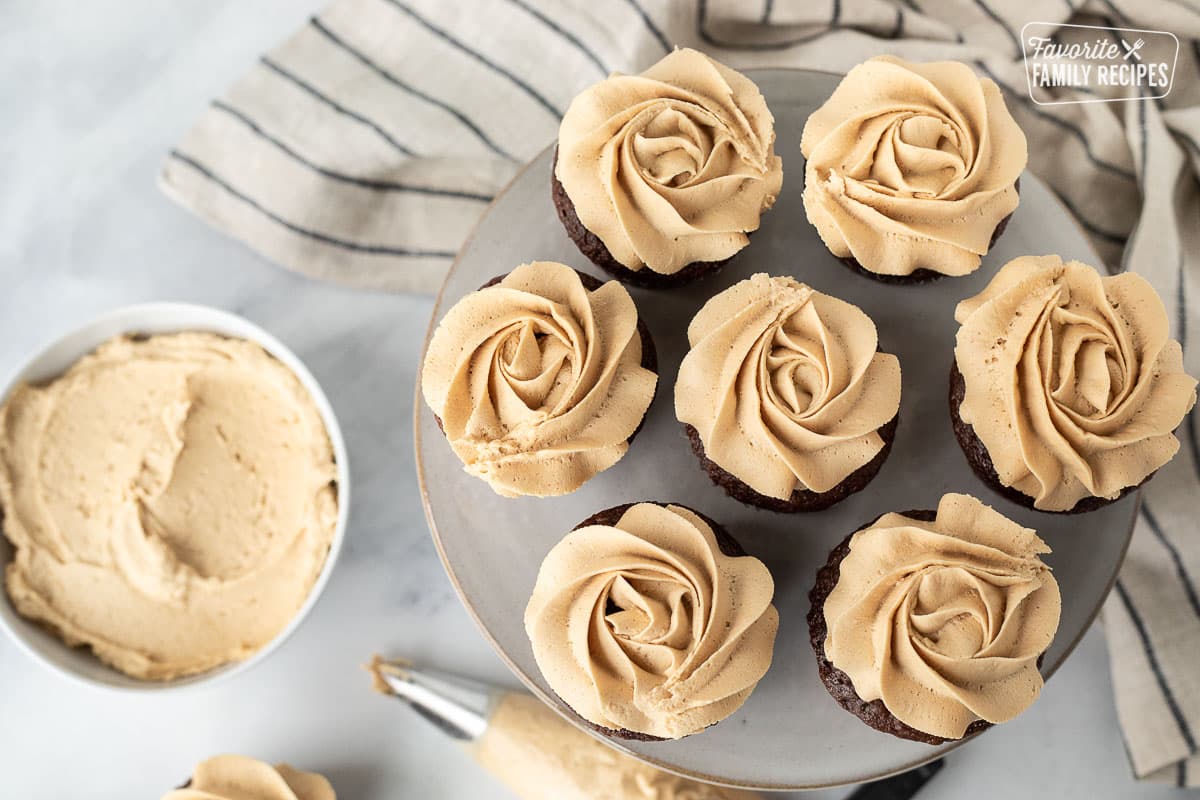 Cake stand of chocolate cupcakes topped with Peanut Butter Frosting swirl.