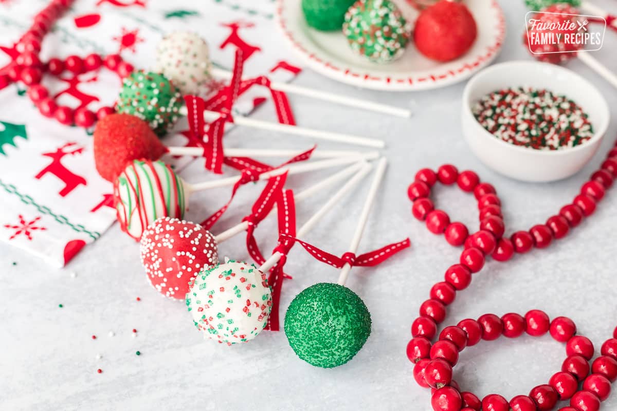 Red, white and green Christmas Cake Pops with bows lined up.