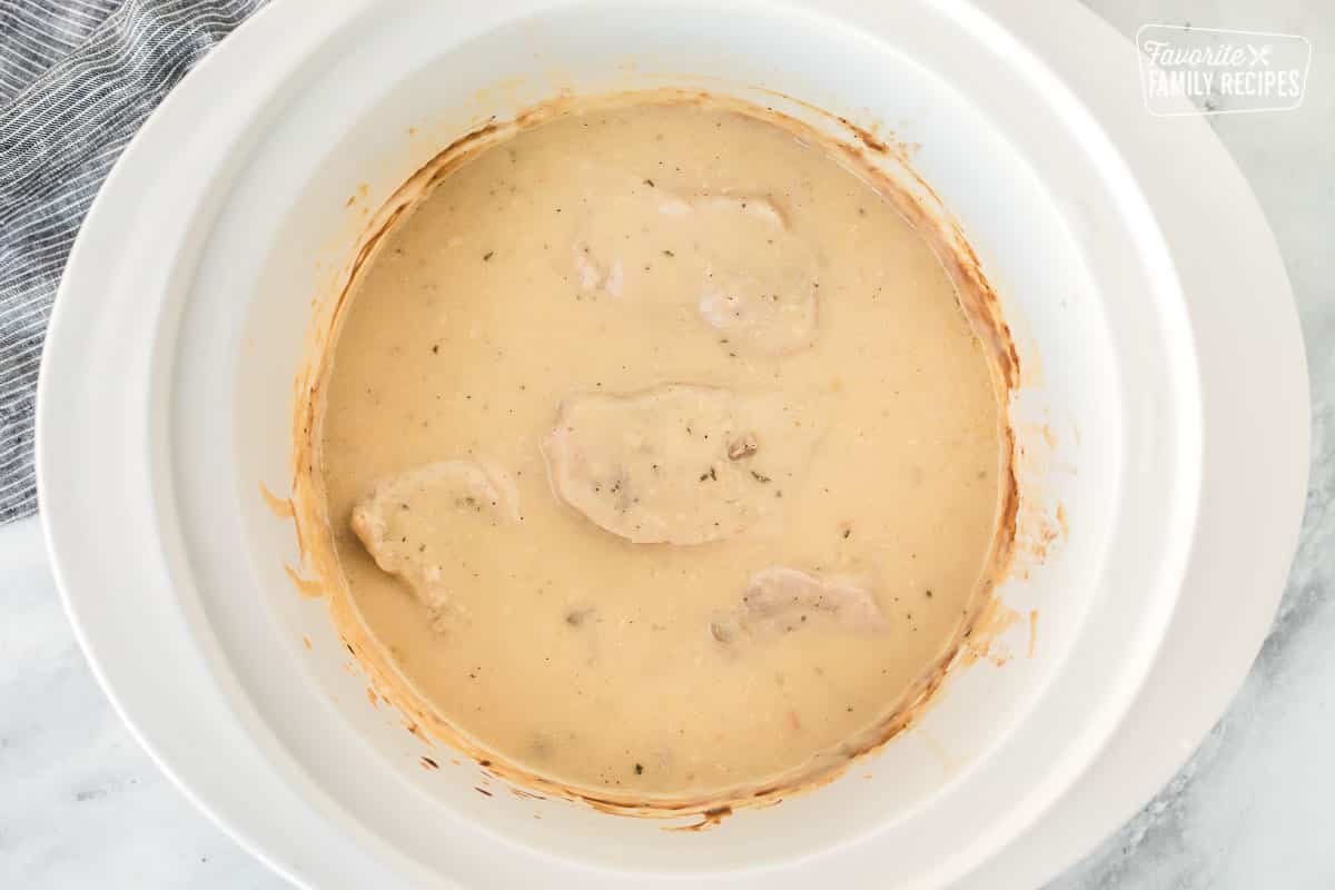 Crock pot with cooked Pork Chops and gravy sauce.