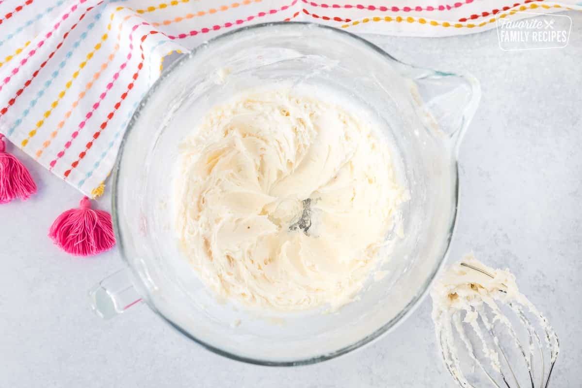 Mixing bowl with creamed butter and sugar with whisk attachment on the side.