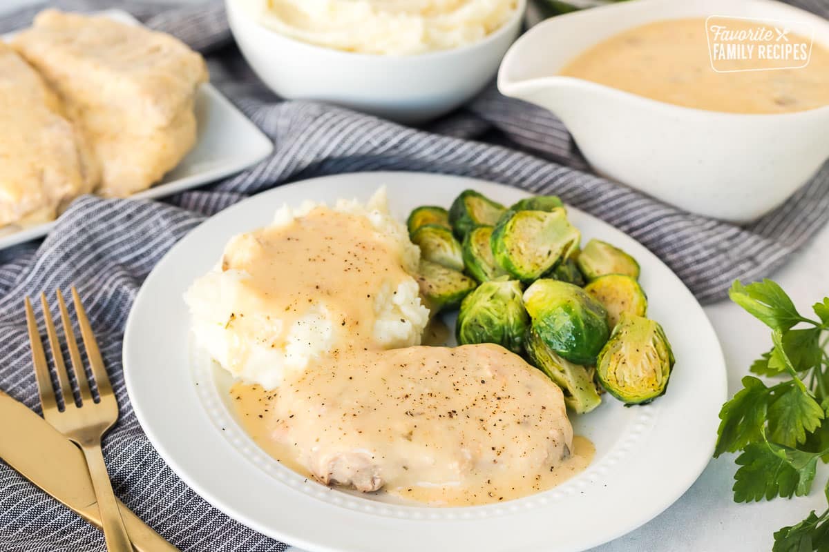 Close up view of Crock Pot Pork Chops with gravy and brussels sprouts.