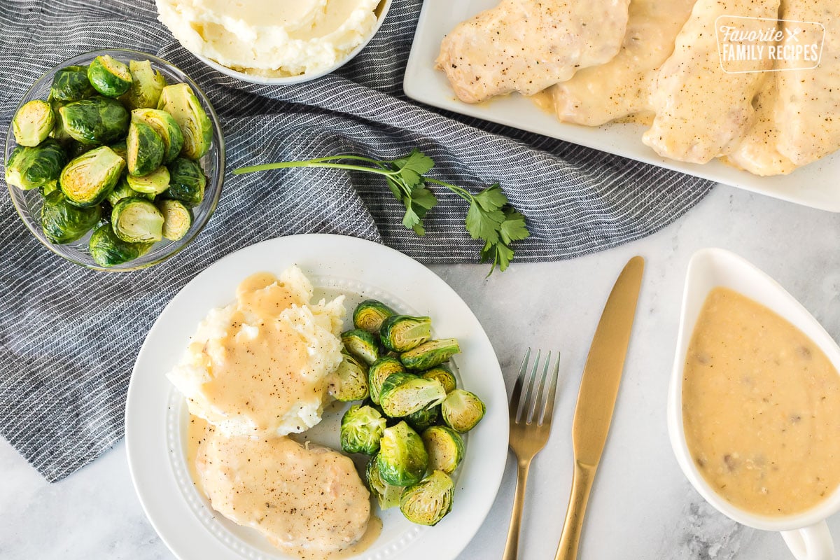 Plate with Crock Pot Pork Chops with gravy and brussels sprouts.