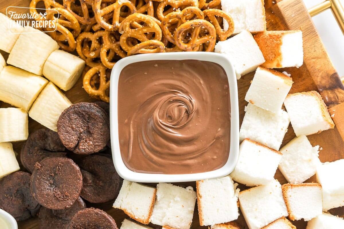 A bowl of melted milk chocolate with bite sized treats for a dessert charcuterie board.
