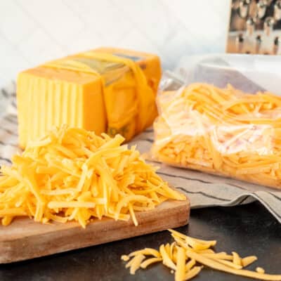 Bag of freeze cheese next to grater and grated cheddar cheese.