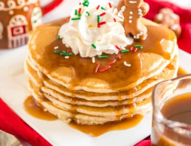 Gingerbread Syrup poured over a stack of pancakes topped with whipped cream and a little gingerbread man