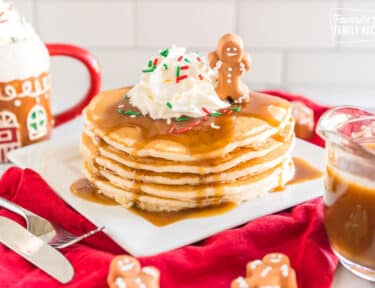 Gingerbread Syrup poured over a stack of pancakes topped with whipped cream and a little gingerbread man