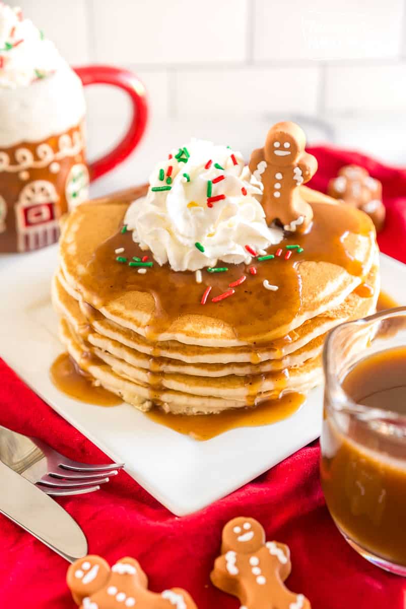 Gingerbread Syrup poured over a stack of pancakes topped with whipped cream and a little gingerbread man