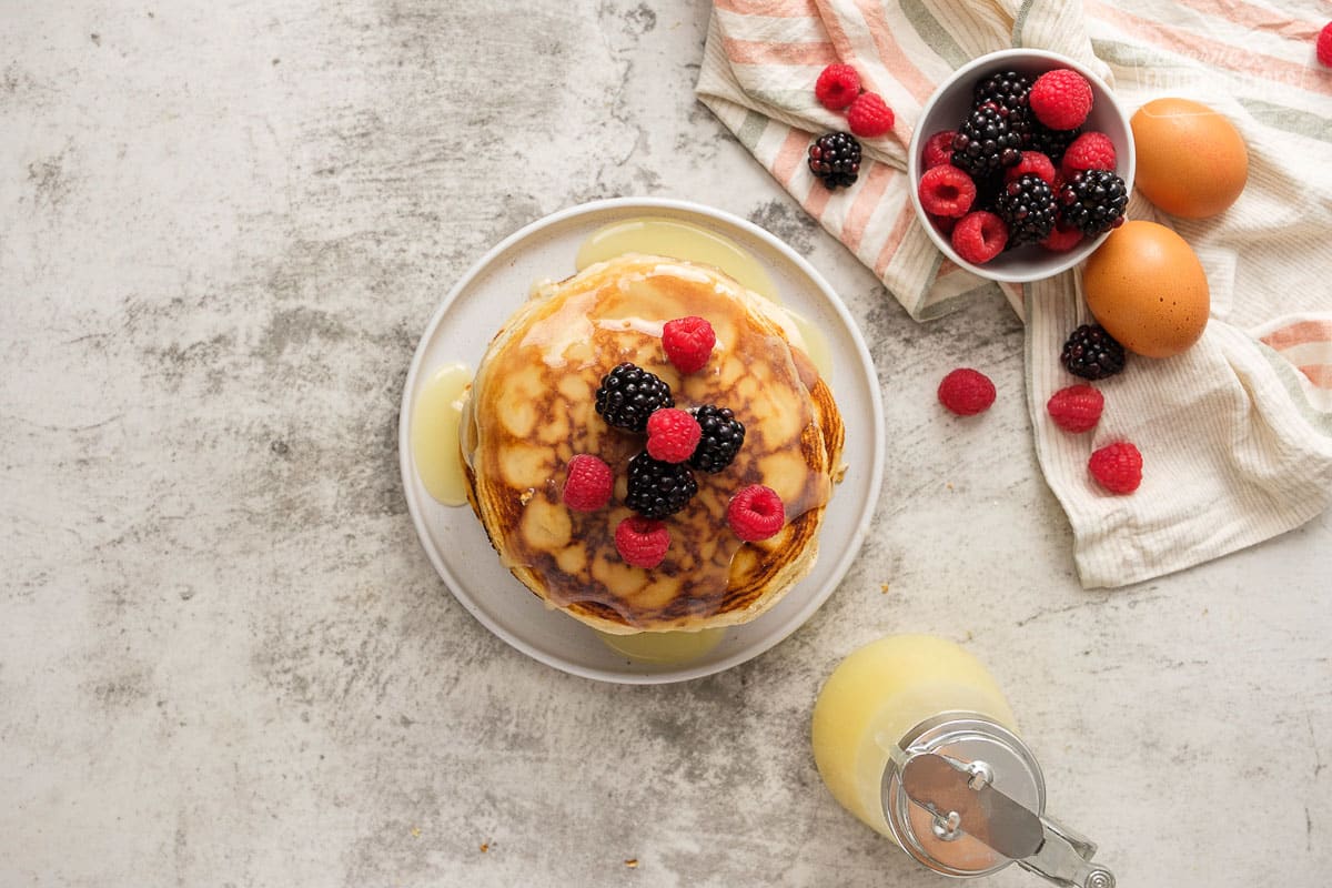 Overhead view of stack of Gluten Free pancakes with syrup and berries