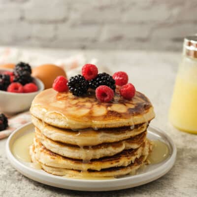Side view of stack of Gluten Free pancakes with syrup and berries