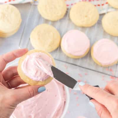 Spreading frosting on a pink Sugar Cookie.