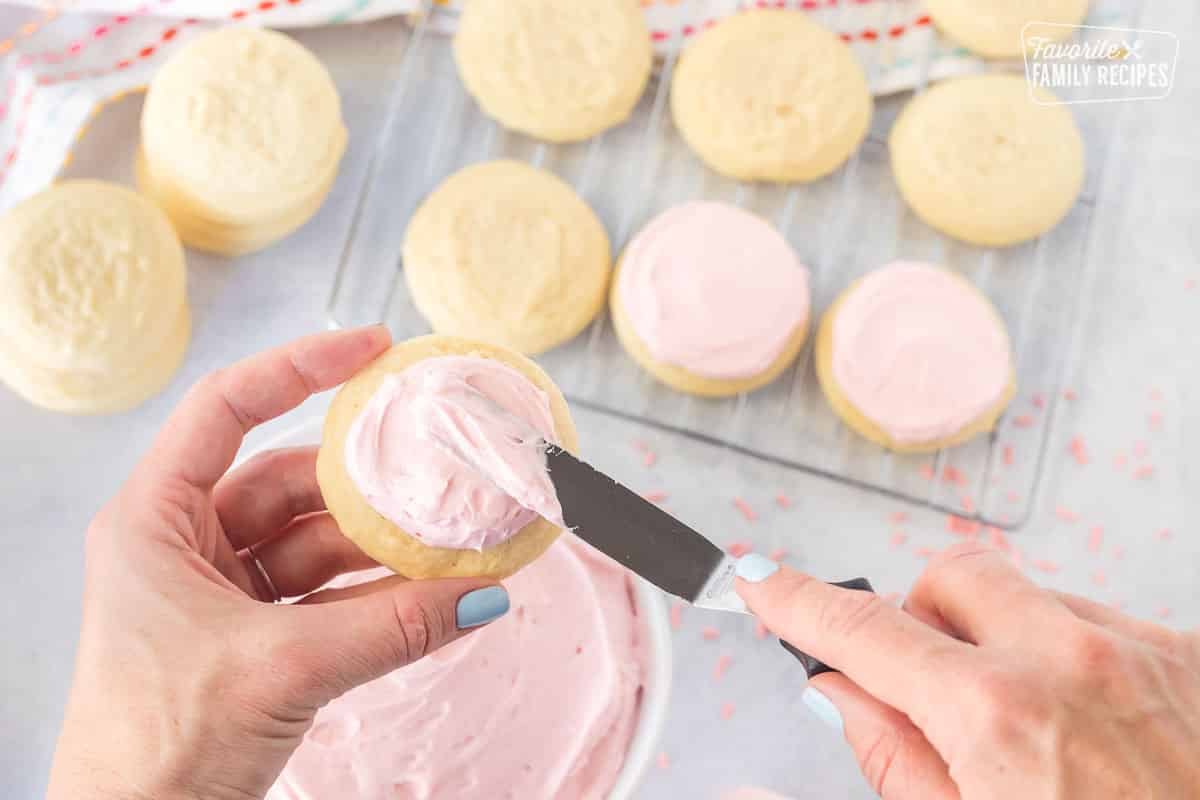 Spreading frosting on a pink Sugar Cookie.