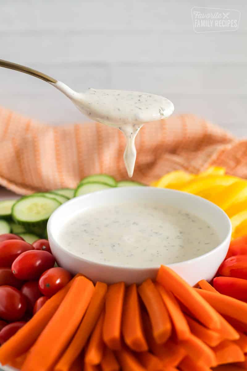 Ranch dressing in a white bowl with a spoonful picking up the ranch. 