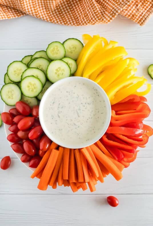 Homemade ranch dressing platter with veggies around it.