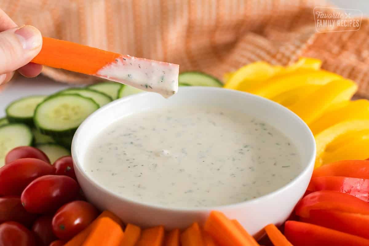 A carrot being dipped in homemade ranch dressing.