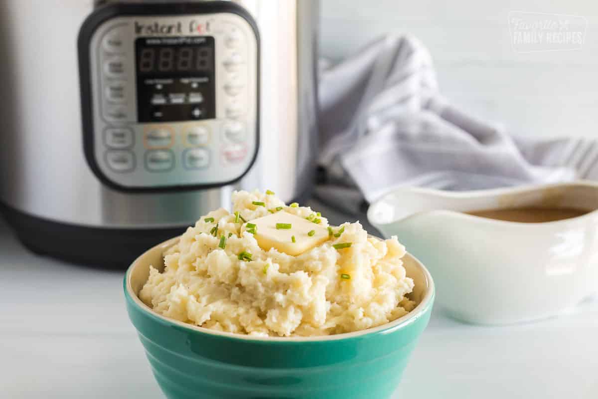 Instant pot mashed potatoes with a slice of butter in a green bowl. 