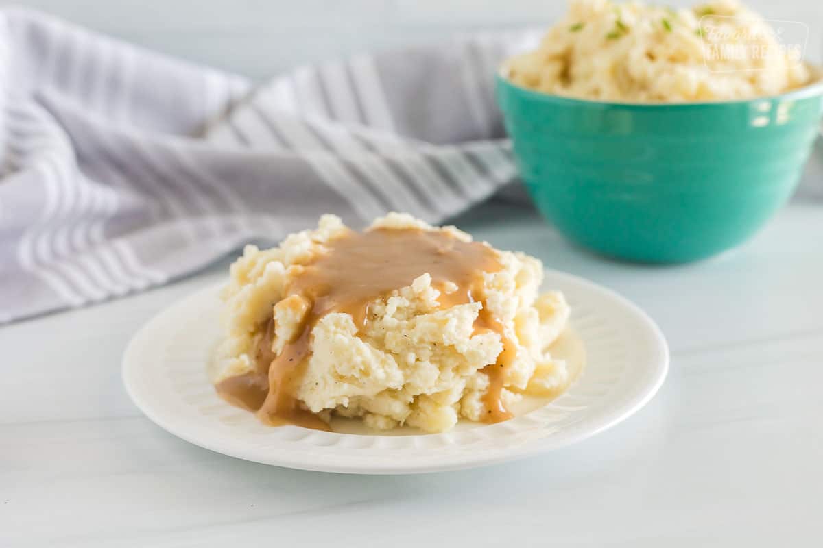 A white plate with mashed potatoes and gravy. 