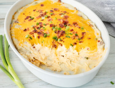 Casserole dish with scooped out areas from Loaded Mashed Potatoes.