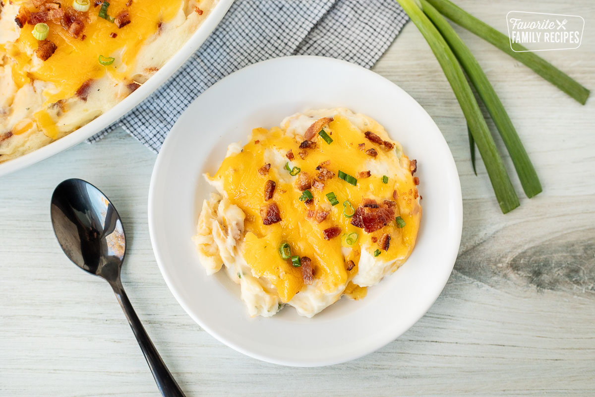 Plate with a serving of Loaded Mashed Potatoes garnished with bacon and green onions.