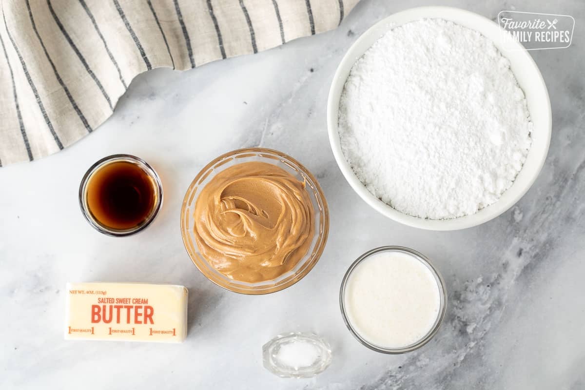 Ingredients to make Peanut Butter Frosting including powdered sugar, peanut butter, vanilla, heavy cream, butter and salt.