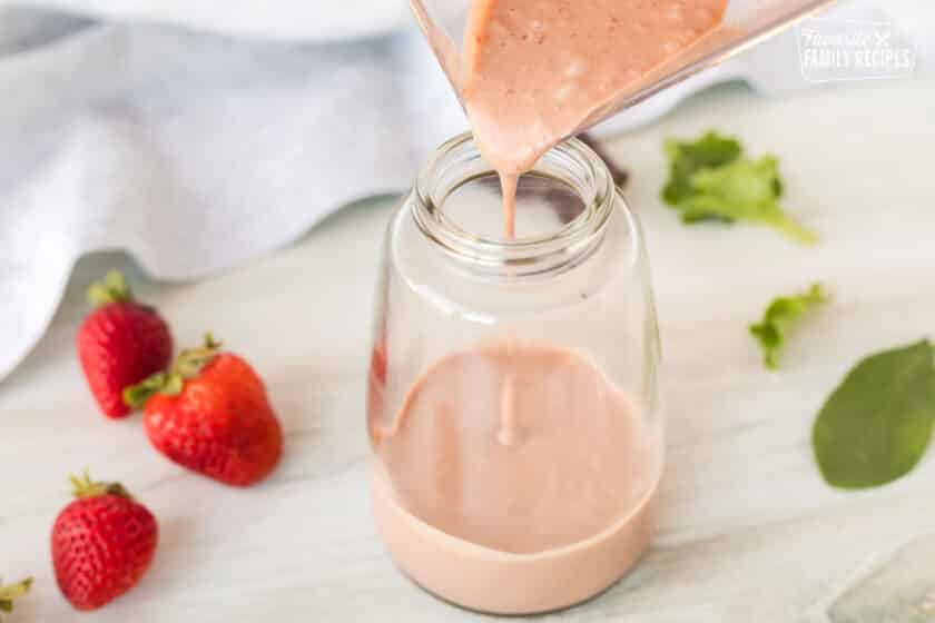 Pouring Strawberry Vinaigrette out of the blender into a dressing jar.