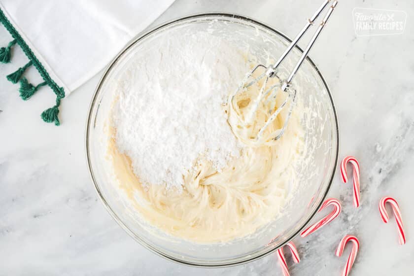 Powdered sugar in mixing bowl of white chocolate frosting.