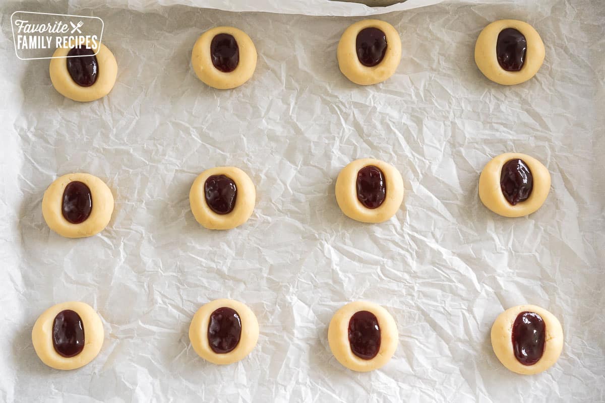 dough balls with pockets of jam on a baking sheet before baking