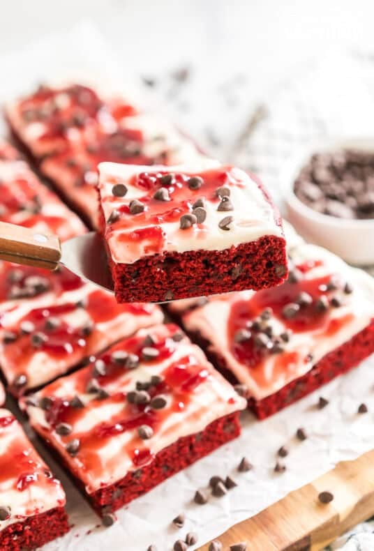 Red Velvet Brownies frosted with cream cheese icing and topped with raspberry topping and chocolate chips