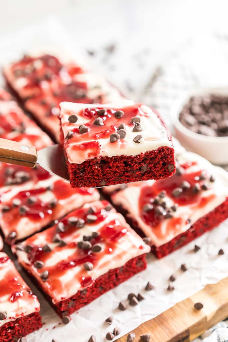 Red Velvet Brownies frosted with cream cheese icing and topped with raspberry topping and chocolate chips