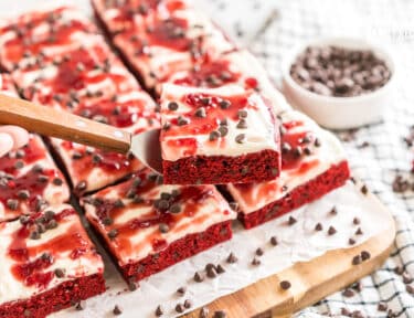 Red Velvet Brownies frosted with cream cheese icing and topped with raspberry topping and chocolate chips