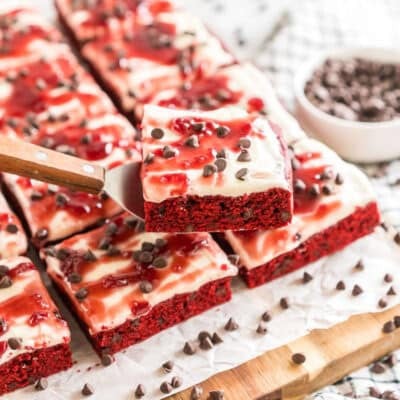 Red Velvet Brownies frosted with cream cheese icing and topped with raspberry topping and chocolate chips