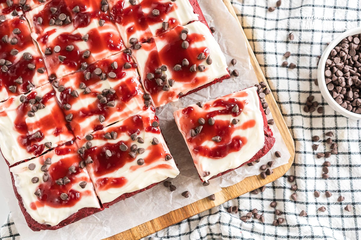 Red Velvet Brownies frosted with cream cheese icing and topped with raspberry topping and chocolate chips